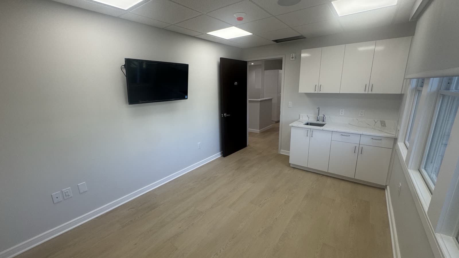 Medical office consult room with wall-mounted commercial display and in-ceiling distributed audio speaker installed by Restrepo Innovations at 50 Summit