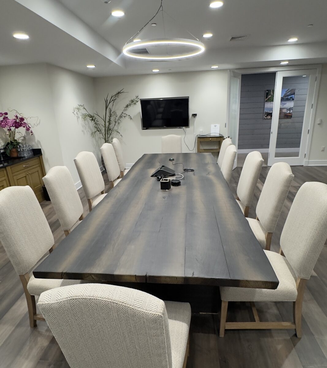 Basking Ridge executive conference room with a long live-edge wood table, upholstered chairs, and a wall-mounted Samsung display at the far end
