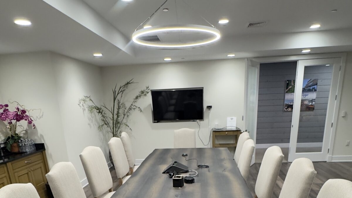 Basking Ridge executive conference room with a live-edge table, upholstered chairs, and a wall-mounted display installed by Restrepo Innovations