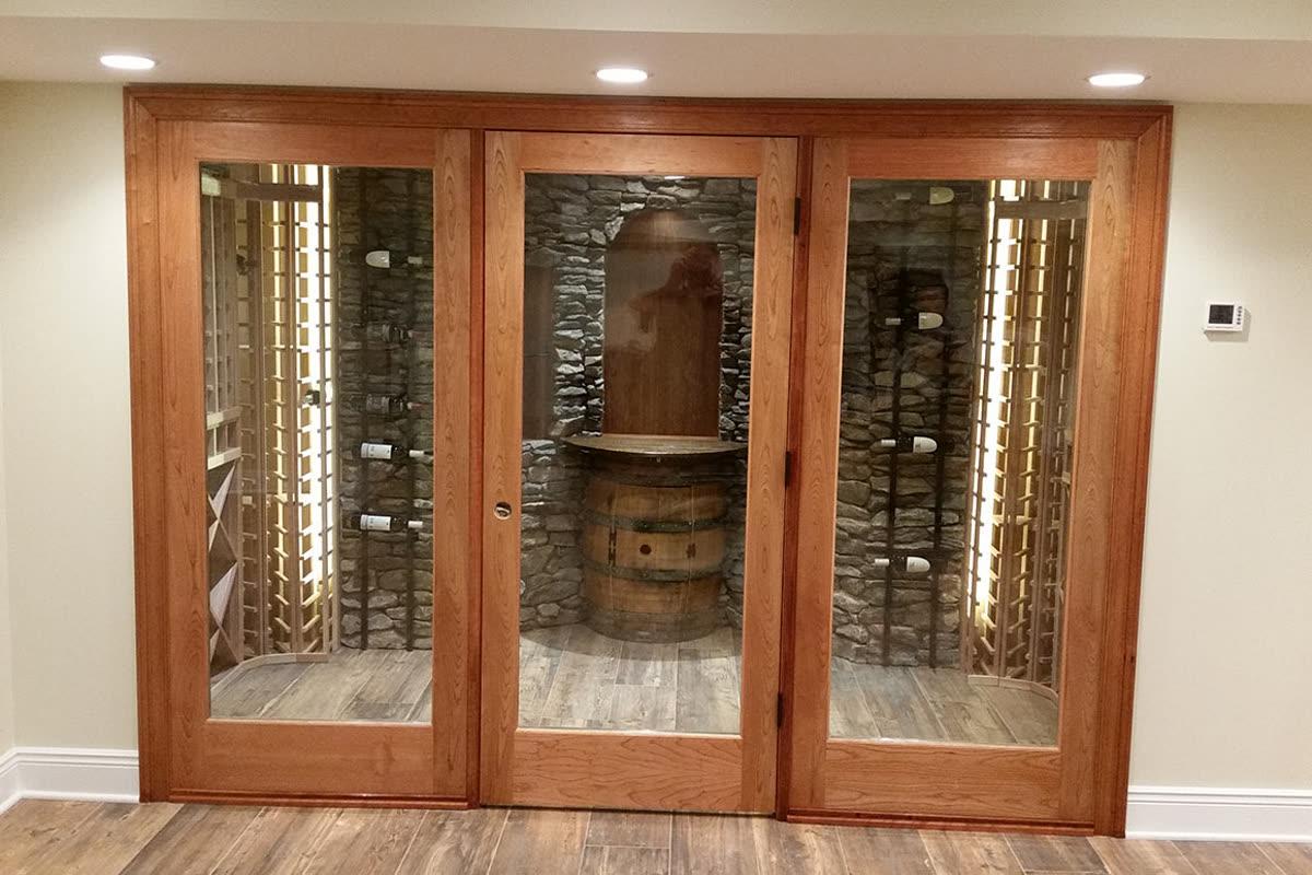 Sinclair Homes custom home builder wine cellar with glass doors, stone walls, and warm interior lighting